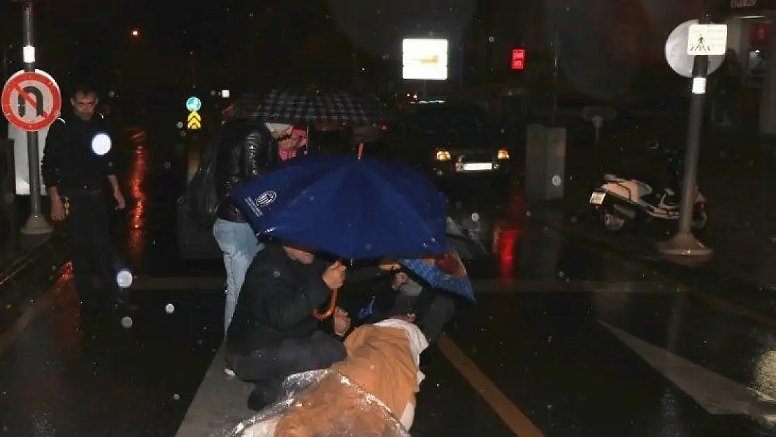 Motosikletten düşen kadını şemsiyelerle yağmurdan korudular