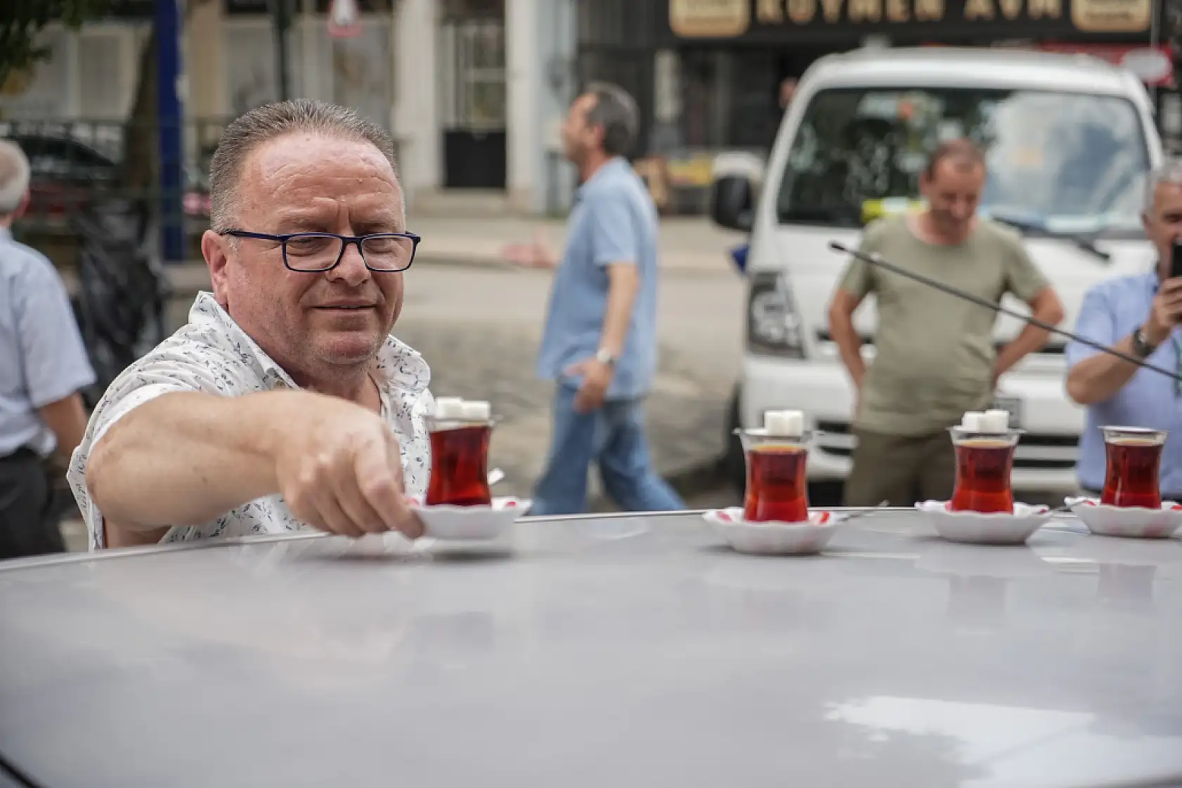 50 metre uzaklıktaki çay ocağından aldığı çayları otomobiliyle taşıyor