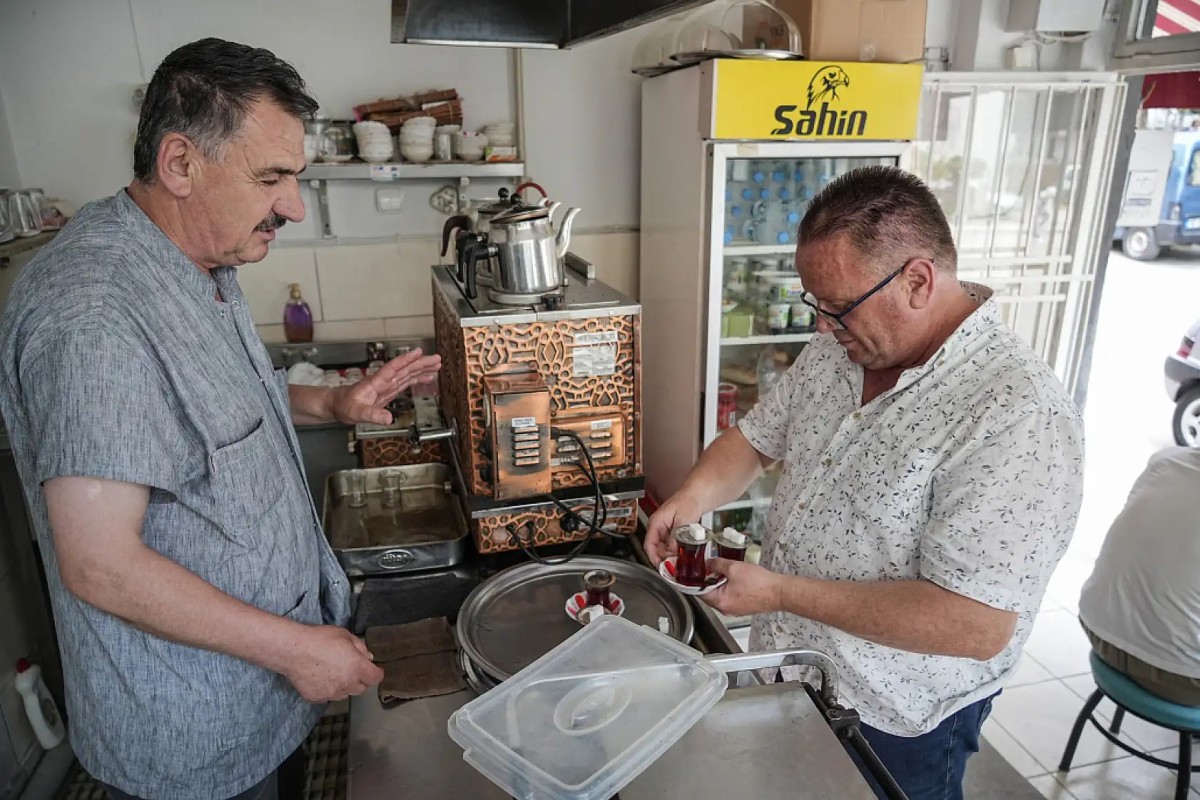 50 metre uzaklıktaki çay ocağından aldığı çayları otomobiliyle taşıyor