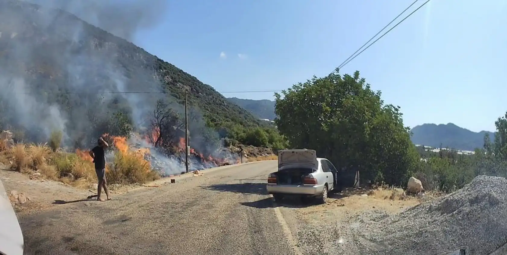 Yol kenarındaki yangını gören tatilci aile alevlere yangın tüpüyle müdahale etti