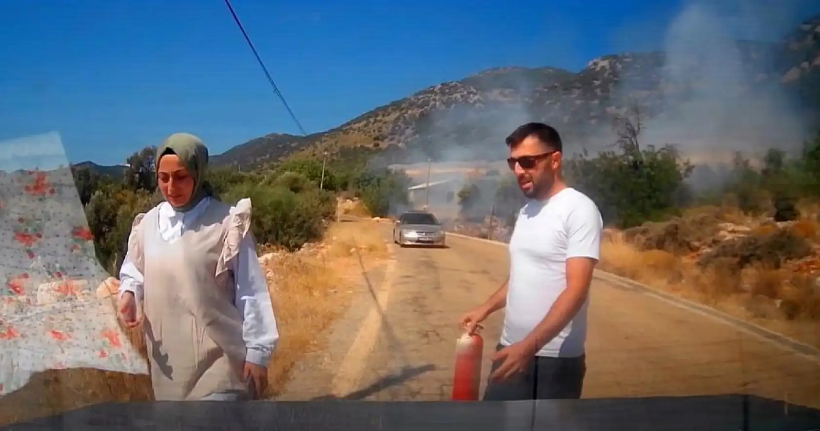 Yol kenarındaki yangını gören tatilci aile alevlere yangın tüpüyle müdahale etti