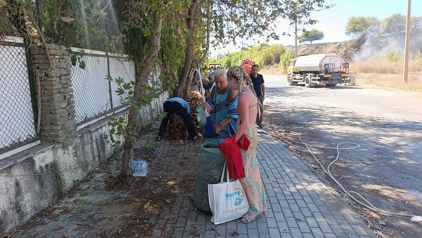 Turistler yangın sonrası otel çevresindeki kurumuş ot ve yaprakları temizledi