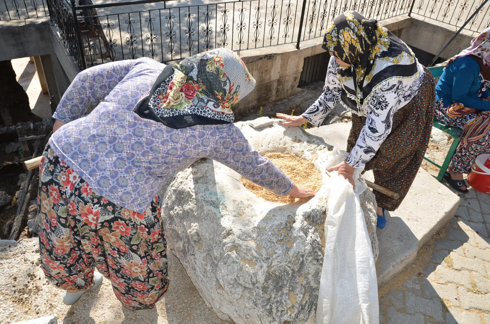 Asırlık dibek taşında buğday dövüp bir taraftan ise erişte ve çorbalık kesiyorlar