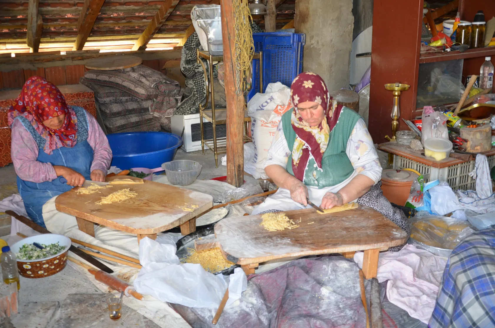 Asırlık dibek taşında buğday dövüp bir taraftan ise erişte ve çorbalık kesiyorlar