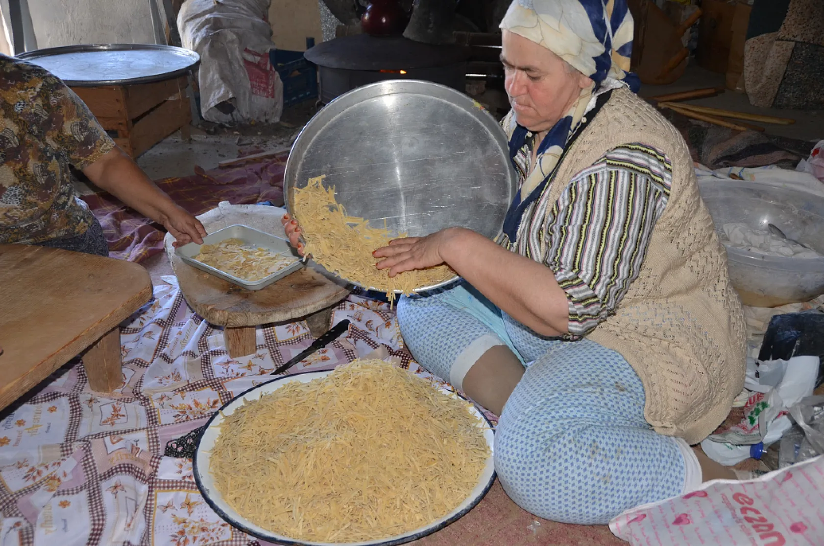 Asırlık dibek taşında buğday dövüp bir taraftan ise erişte ve çorbalık kesiyorlar