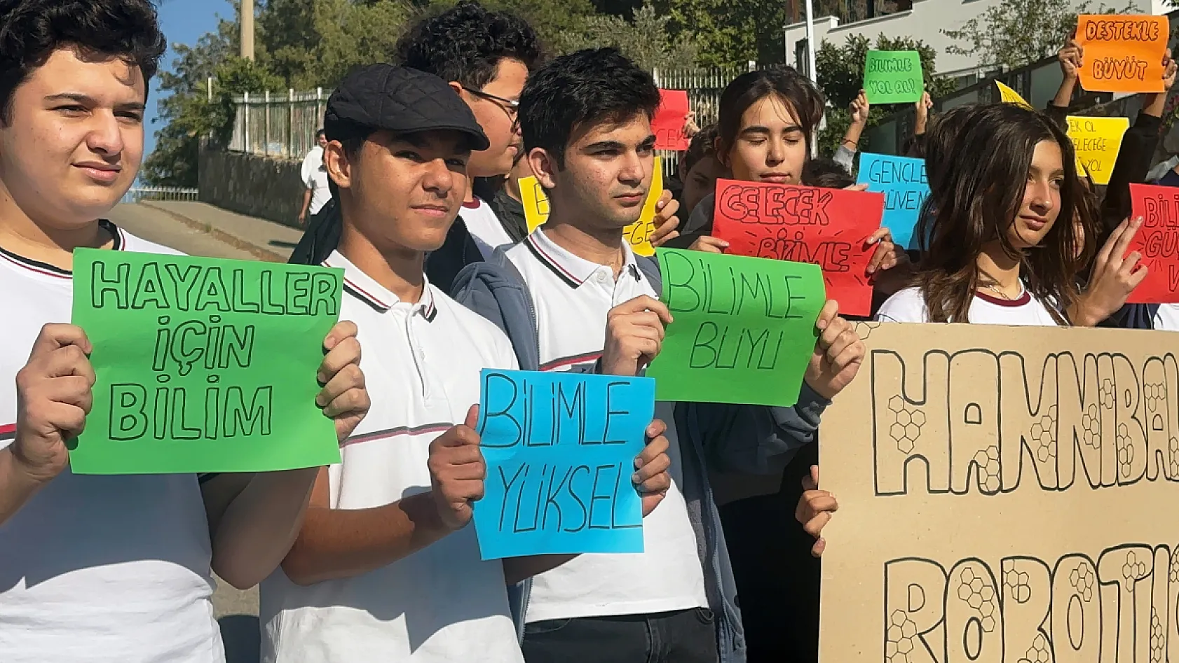 Öğrenciler ellerinde pankartlarla yarışmaya katılmak için destek istedi